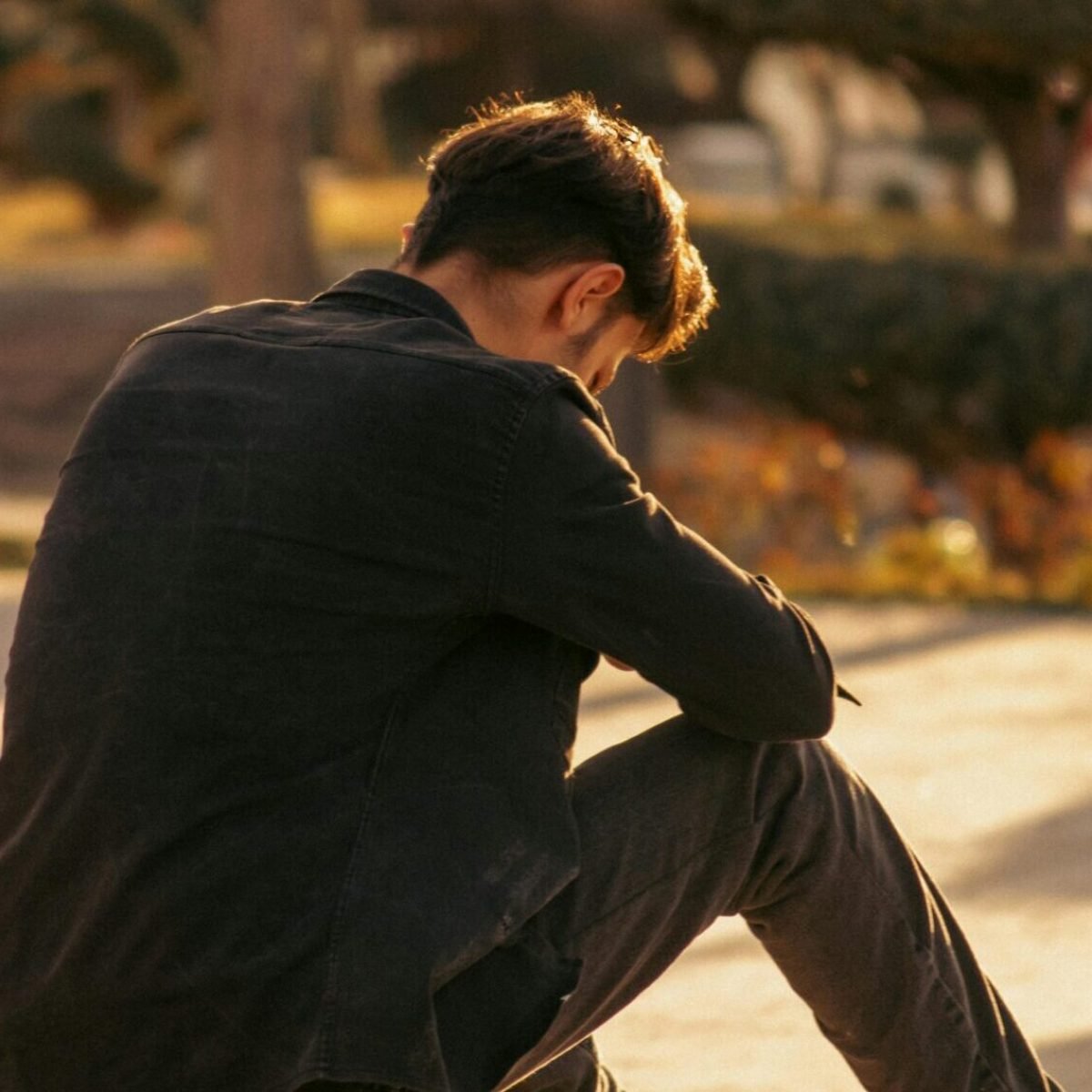 man sitting alone looking down thinking